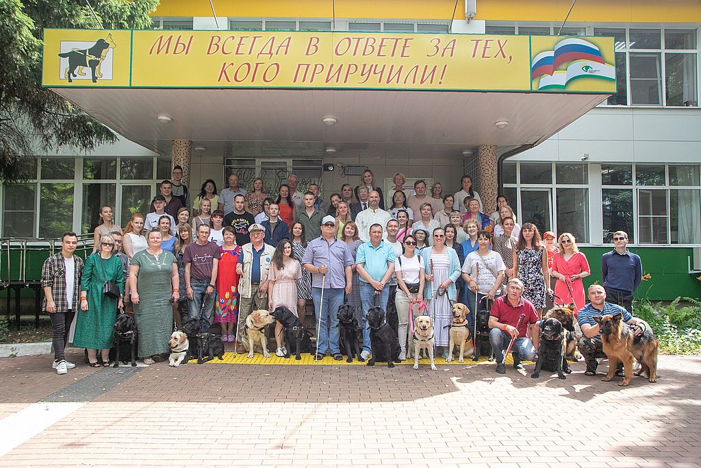 здание школы собак. На крыльце стоят учащиеся со своими питомцами
